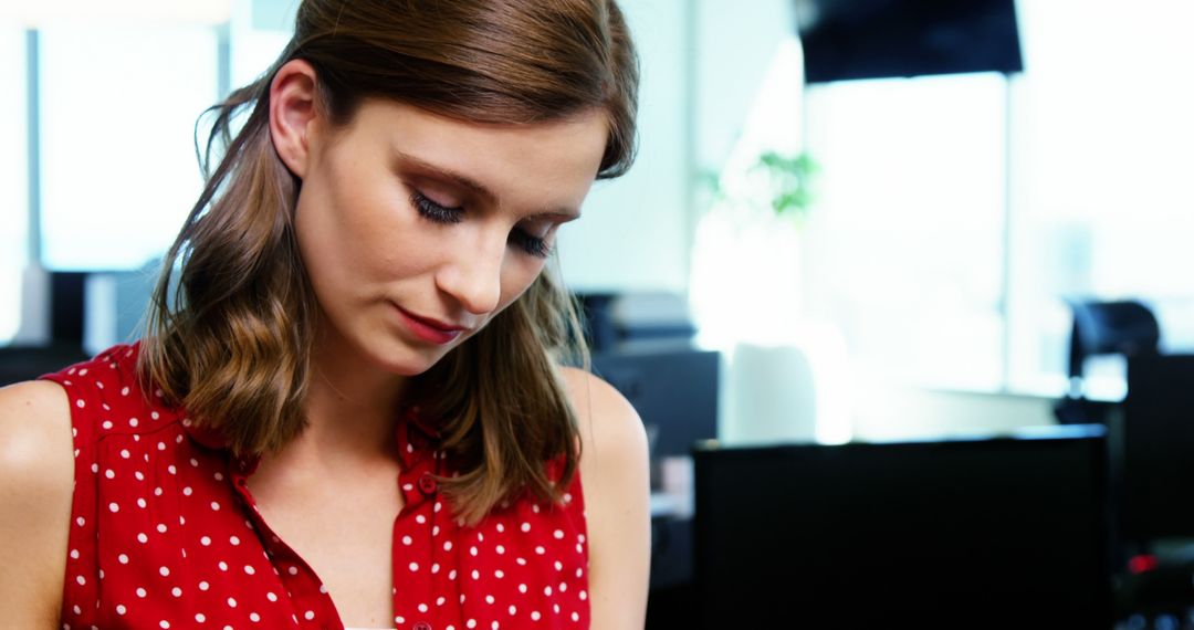 Focused young businesswoman in red polka dot blouse at workspace - Free Images, Stock Photos and Pictures on Pikwizard.com