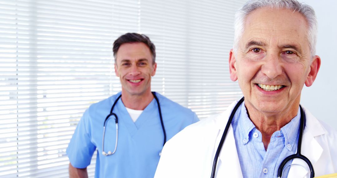 Smiling elderly doctor with colleague in blue scrubs - Free Images, Stock Photos and Pictures on Pikwizard.com