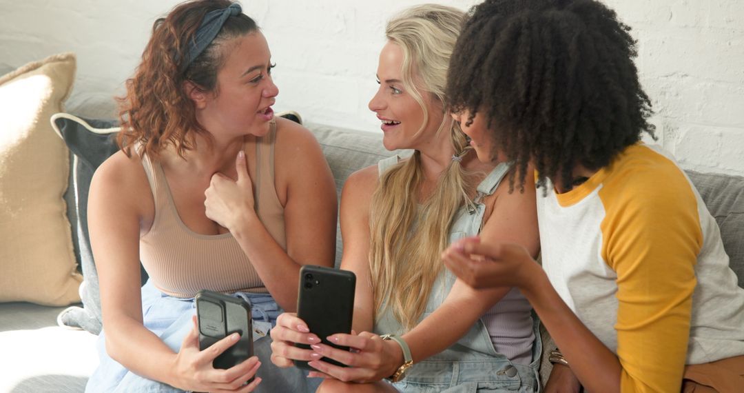 Diverse Female Friends Chatting and Relaxing on Couch with Smartphones