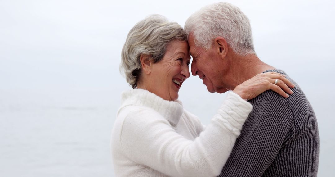 Happy Senior Couple Embracing Outdoors by the Beach - Free Images, Stock Photos and Pictures on Pikwizard.com