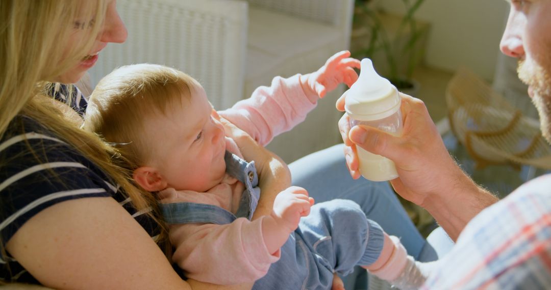 Parents Feeding Baby Daughter with Bottle at Home - Free Images, Stock Photos and Pictures on Pikwizard.com