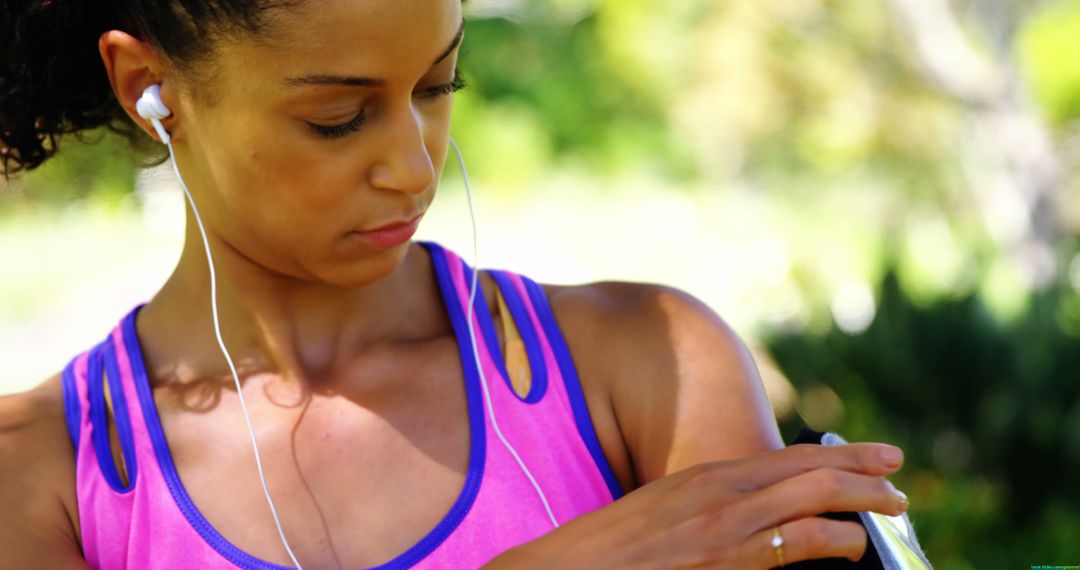 Fit Woman Adjusting Smartphone Armband While Listening to Music Outdoors - Free Images, Stock Photos and Pictures on Pikwizard.com