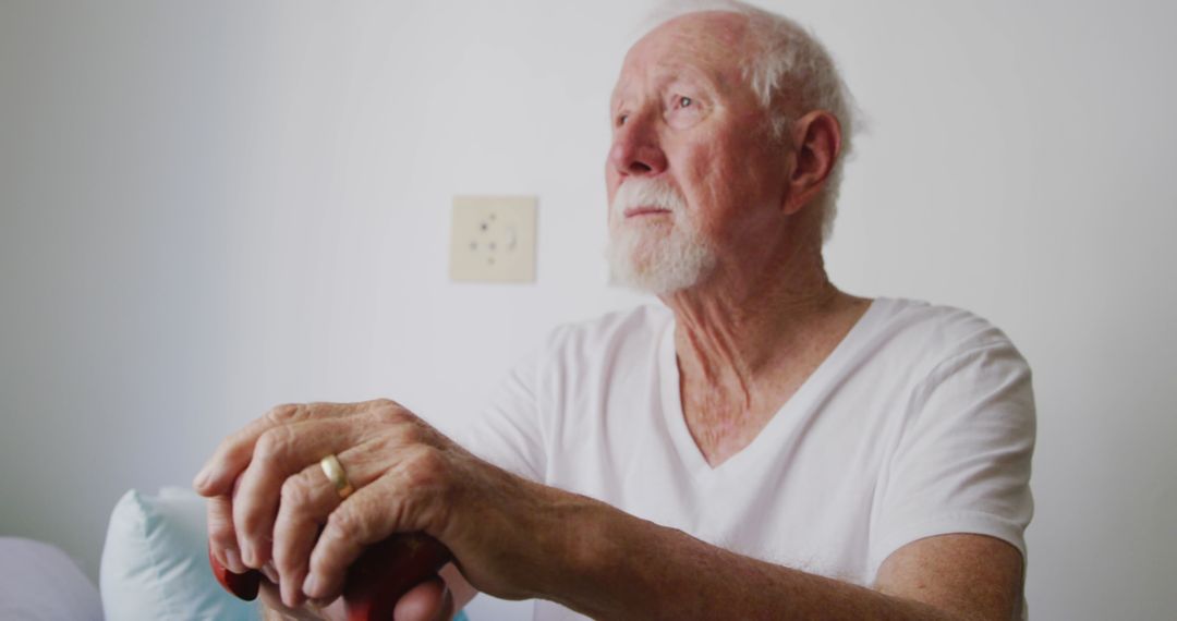 Senior man reflecting with walking stick in retirement home