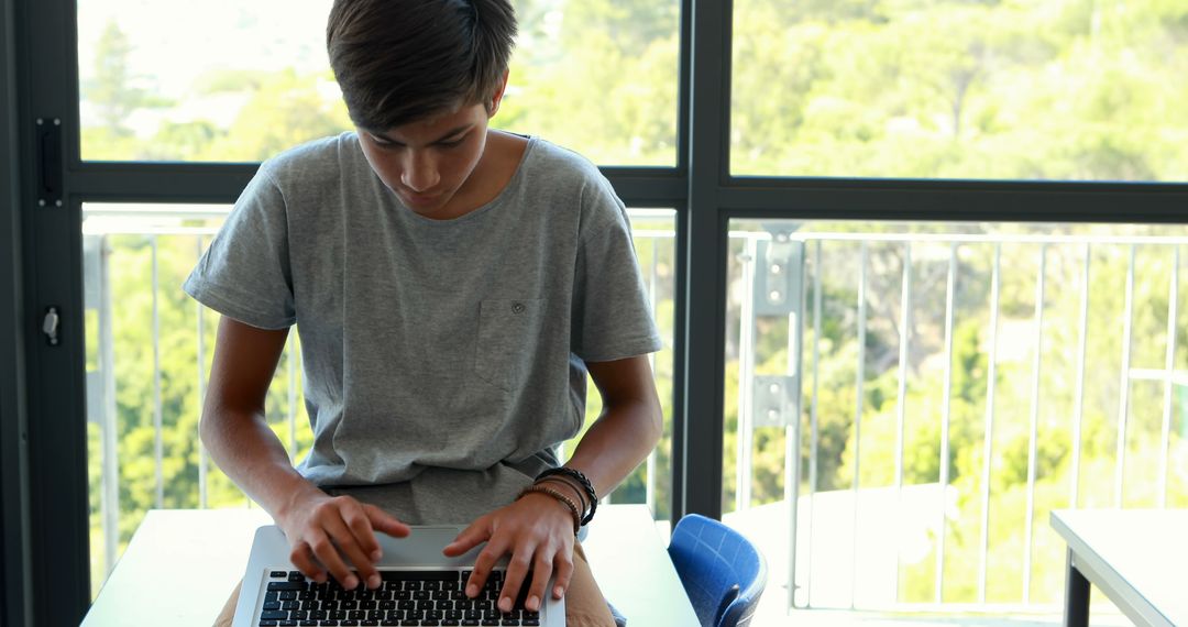 Teenager Using Laptop at Home Near Window - Free Images, Stock Photos and Pictures on Pikwizard.com