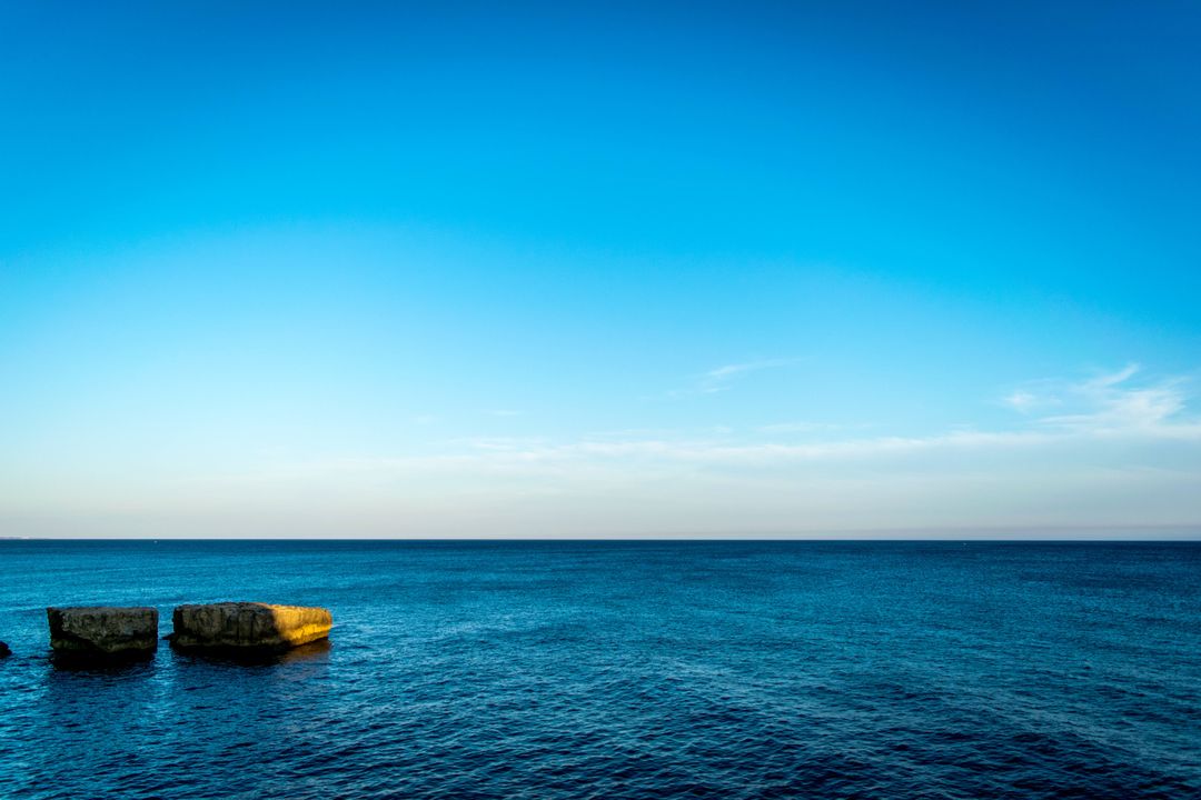 Calm Blue Sea with Clear Sky and Rock Formations - Free Images, Stock Photos and Pictures on Pikwizard.com