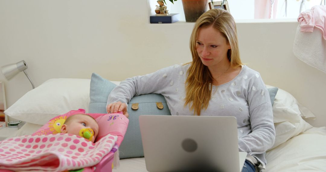 Multitasking Mother Working on Laptop While Caring for Baby - Free Images, Stock Photos and Pictures on Pikwizard.com