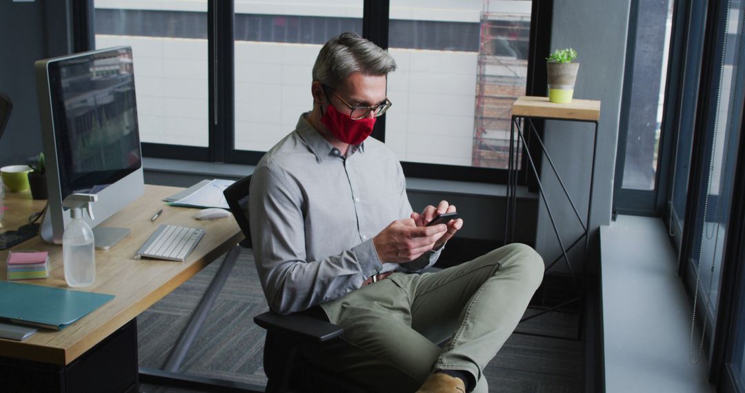 Businessperson Wearing Mask Using Smartphone in Modern Office - Free Images, Stock Photos and Pictures on Pikwizard.com