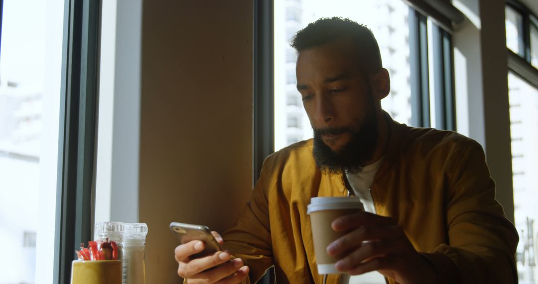 Man with Coffee Cup Using Smartphone in Cafe - Free Images, Stock Photos and Pictures on Pikwizard.com