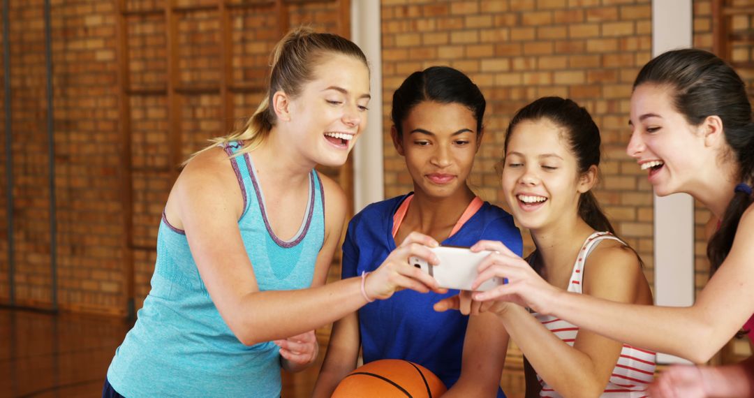 Teenage Girls Smiling and Looking at Smartphone in Gym - Free Images, Stock Photos and Pictures on Pikwizard.com