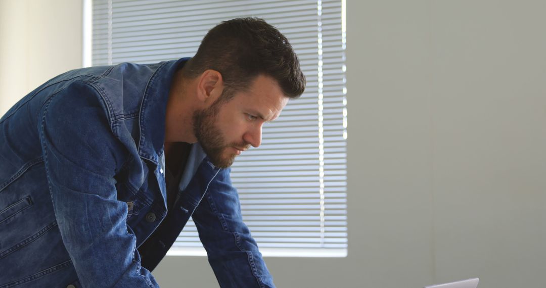 Man in Denim Jacket Working on Laptop in Office - Free Images, Stock Photos and Pictures on Pikwizard.com