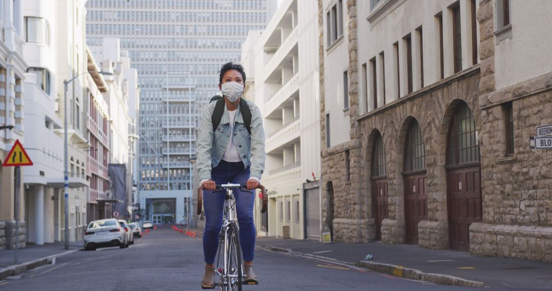 Young Woman Wearing Face Mask Riding Bicycle Through Urban Street - Free Images, Stock Photos and Pictures on Pikwizard.com