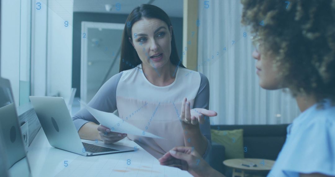 Two Women Collaborating in modern Office with Laptop and Documents