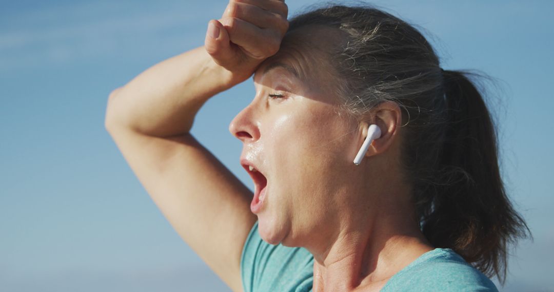 Exercising Woman Wiping Sweat Wearing Wireless Earbuds in Summer Heat - Free Images, Stock Photos and Pictures on Pikwizard.com