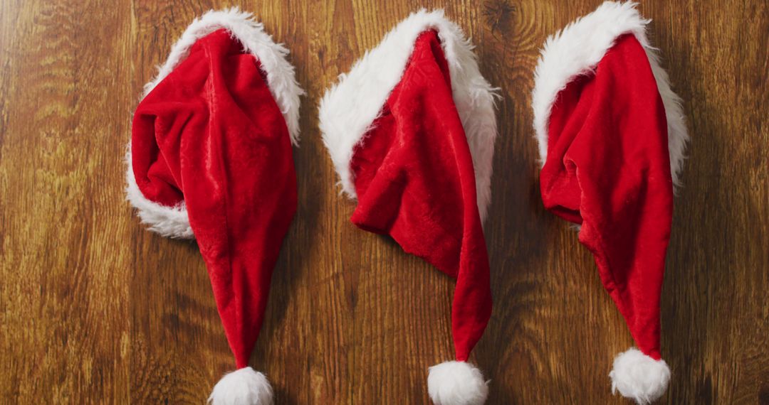 Three Santa Hats on Wooden Surface - Free Images, Stock Photos and Pictures on Pikwizard.com