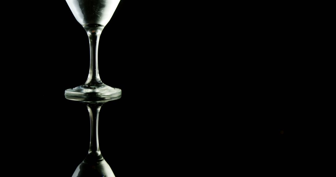 A wine glass is silhouetted against a dark background, creating a minimalist and elegant visual - Free Images, Stock Photos and Pictures on Pikwizard.com