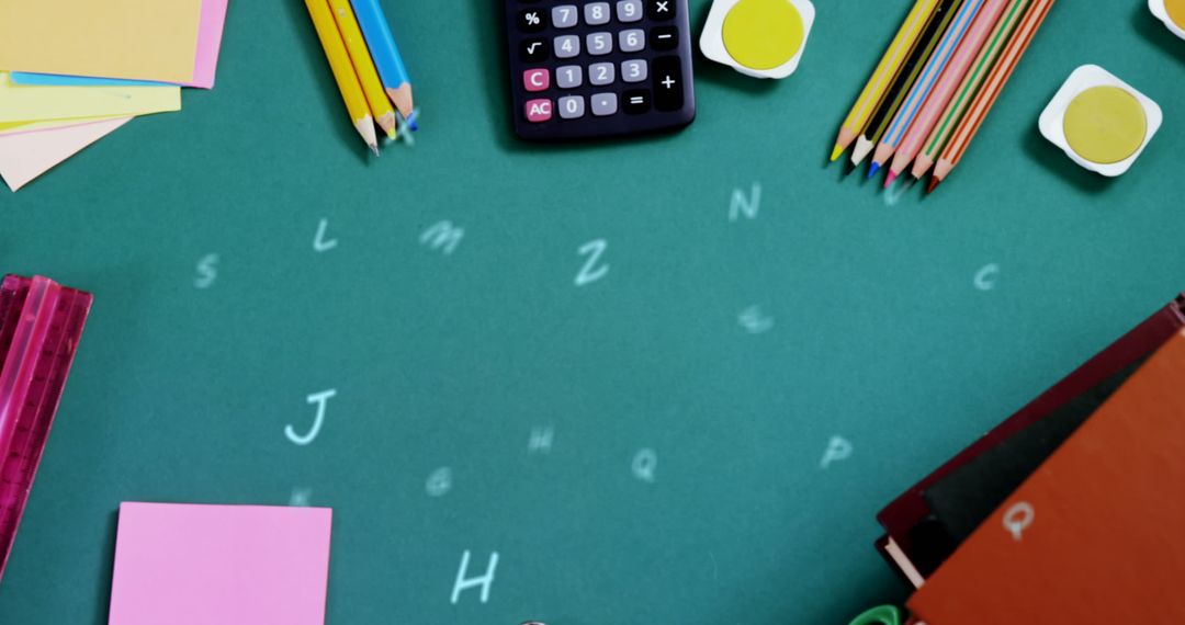 Colorful Stationery on Green Desk with Floating Alphabets