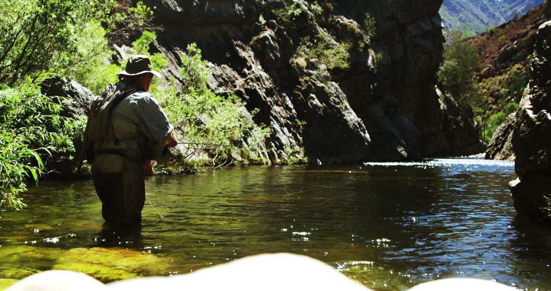 Fly fisherman wading river in mountainous landscape on sunny day - Free Images, Stock Photos and Pictures on Pikwizard.com