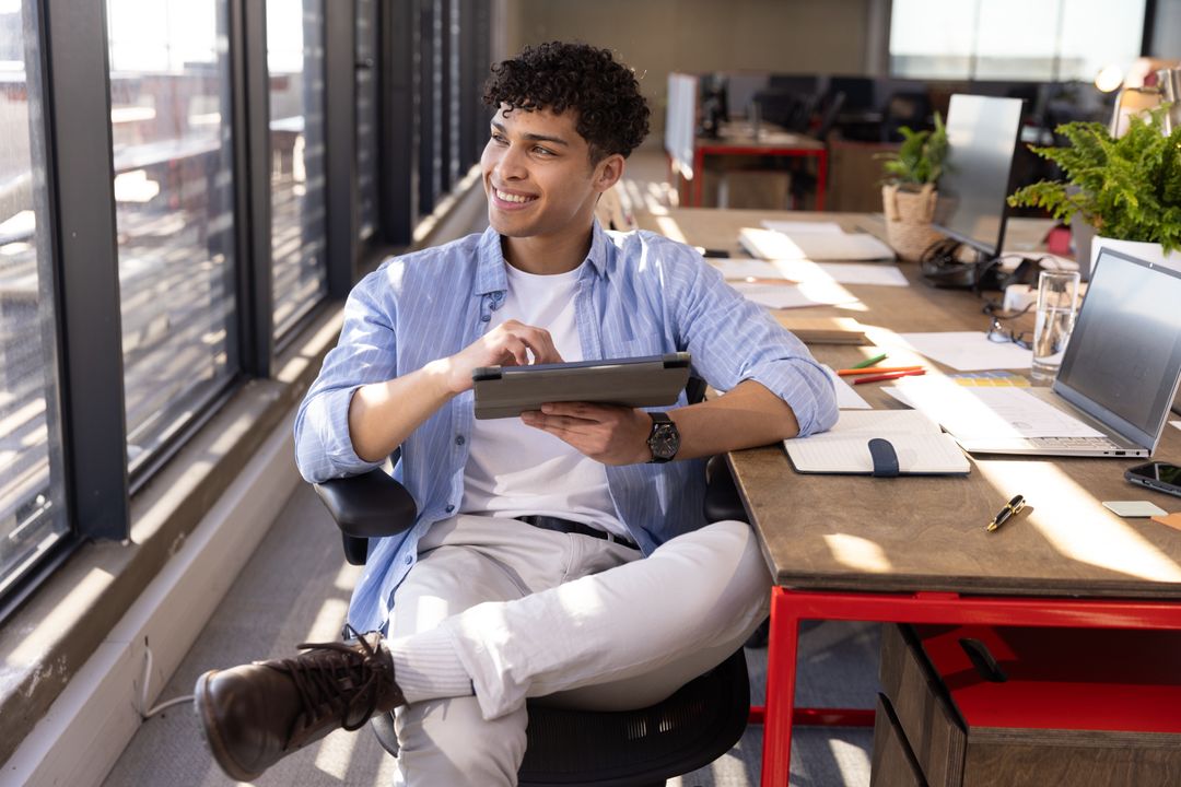 Man Relaxing in Office with Tablet and Open Workspace