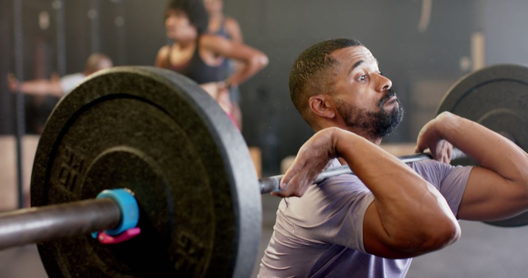 Focused man lifting barbell in gym with determination - Free Images, Stock Photos and Pictures on Pikwizard.com