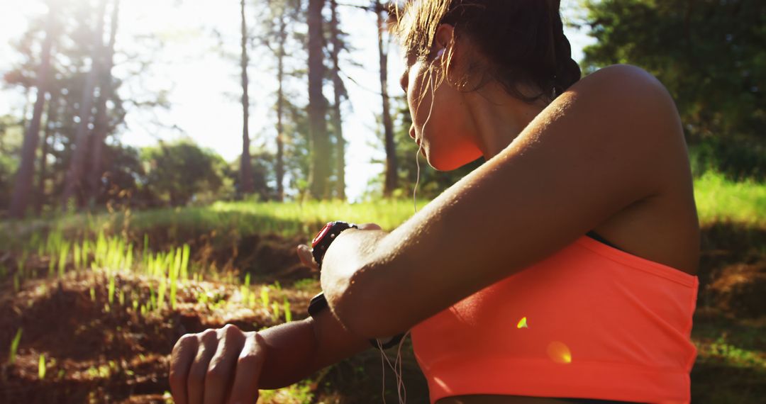 Female Athlete Checking Smartwatch During Outdoor Workout in Forest - Free Images, Stock Photos and Pictures on Pikwizard.com