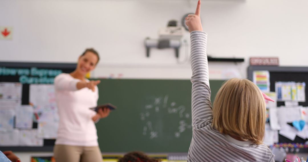 Child Raising Hand While Teacher Engages Class in Lesson