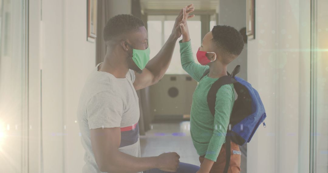 Happy Father and Son High-Fiving in Hallway with Face Masks