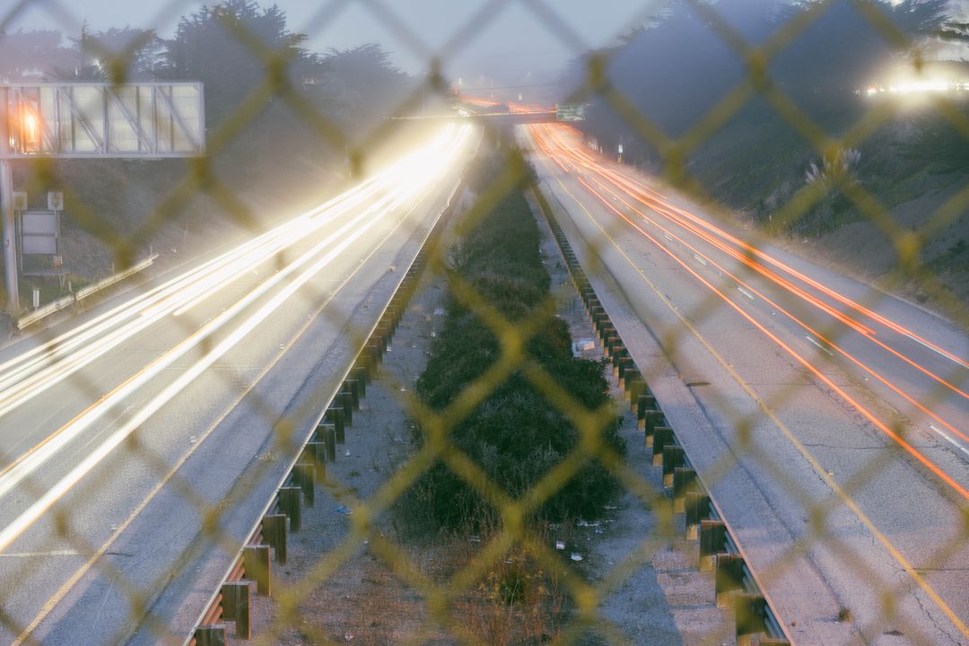 Light Trails of Traffic on Highway Through Chain Link Fence at Night - Free Images, Stock Photos and Pictures on Pikwizard.com