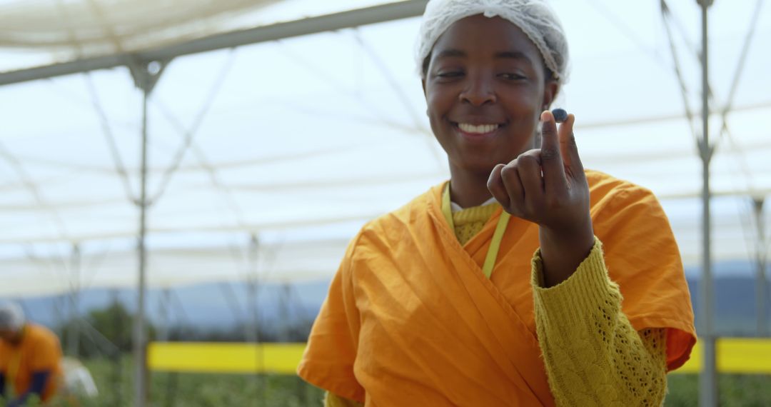 Smiling Farm Worker Holding Blueberry in Agricultural Field - Free Images, Stock Photos and Pictures on Pikwizard.com