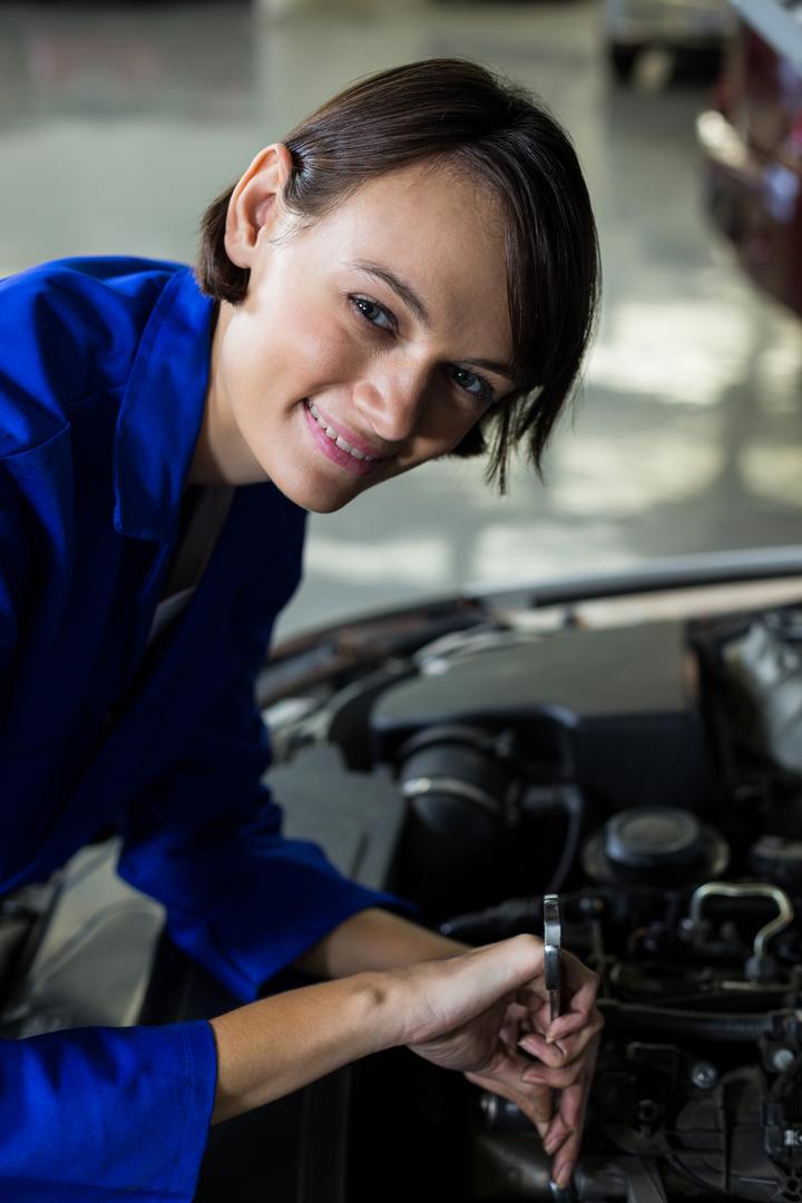 Female mechanic smiling while servicing a car - Free Images, Stock Photos and Pictures on Pikwizard.com