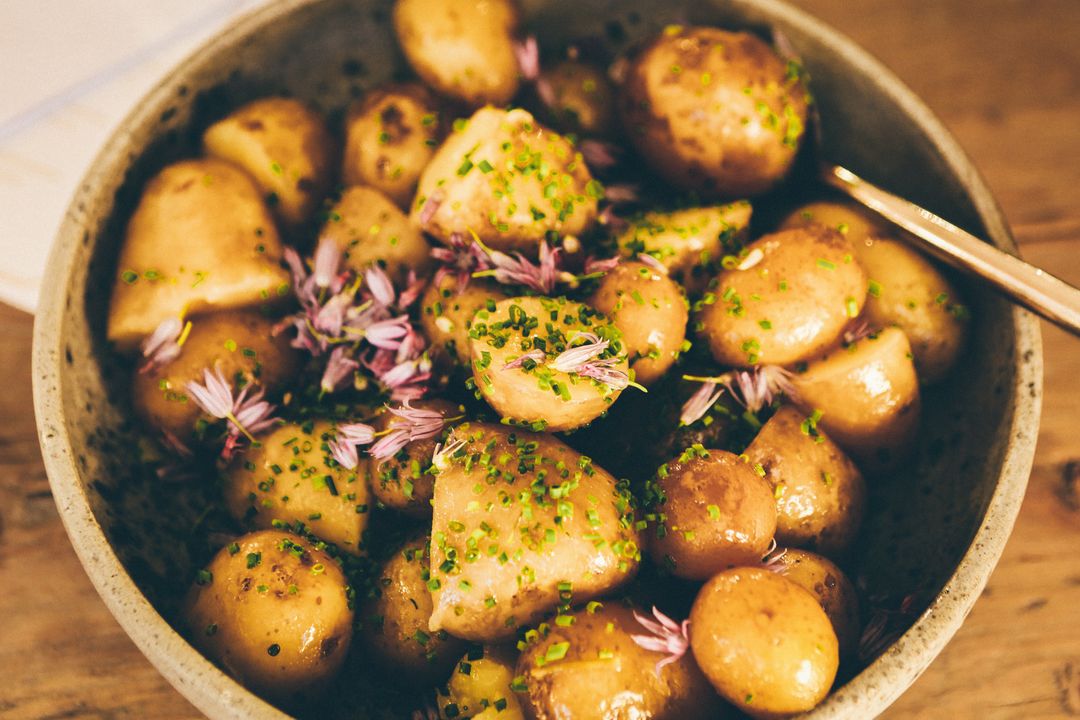 Brown Butter New Potatoes with Chives and Chive Blossoms in Rustic Serving Bowl