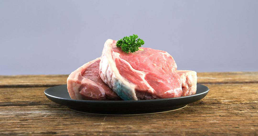 Fresh Raw Pork Chops on Black Plate with Parsley Garnish - Free Images, Stock Photos and Pictures on Pikwizard.com