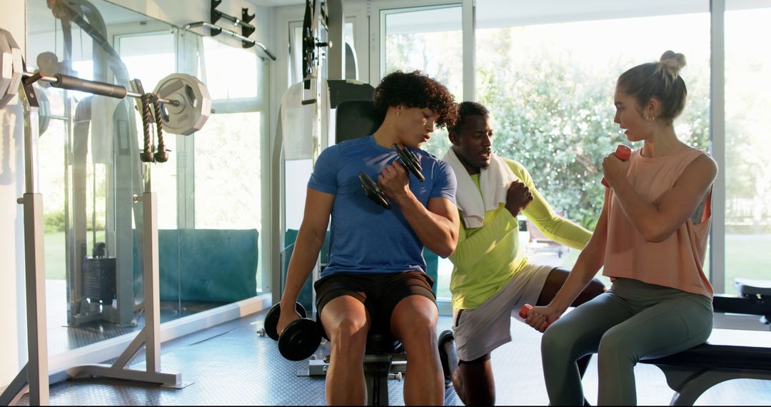 Trainer Guides Young Couple's Dumbbell Workout in Modern Gym