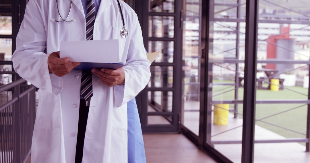 Doctor Holding Documents in Modern Hospital Corridor - Free Images, Stock Photos and Pictures on Pikwizard.com