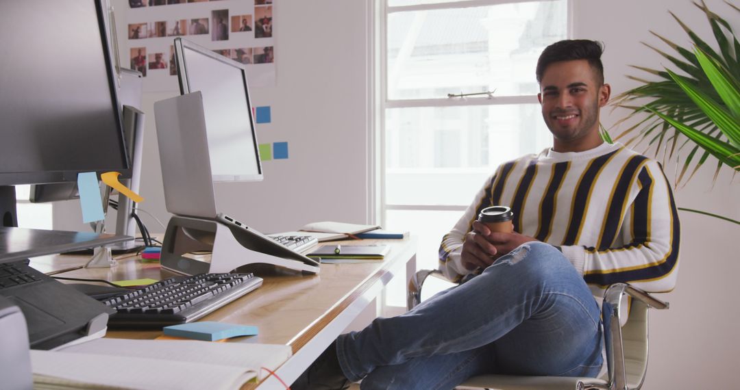Smiling Man in Creative Office with Coffee and Digital Devices