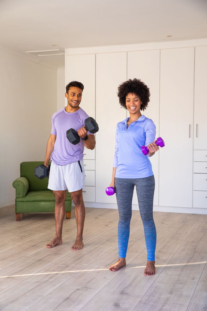Diverse Couple Exercising with Dumbbells in Bright Living Room