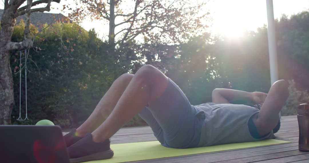 Man Exercising Outdoors on Mat with Laptop Nearby at Sunset - Free Images, Stock Photos and Pictures on Pikwizard.com