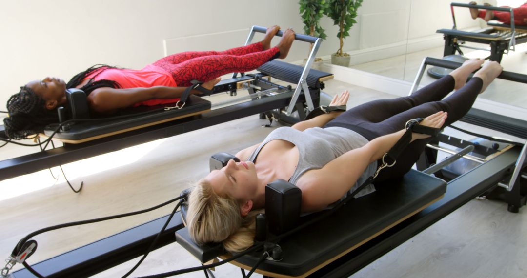 Women practicing Pilates on reformer machines in modern fitness studio - Free Images, Stock Photos and Pictures on Pikwizard.com