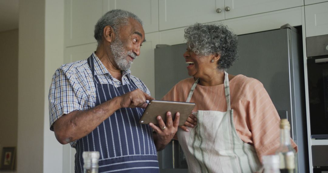 Happy african american senior couple cooking together, using tablet - Free Images, Stock Photos and Pictures on Pikwizard.com