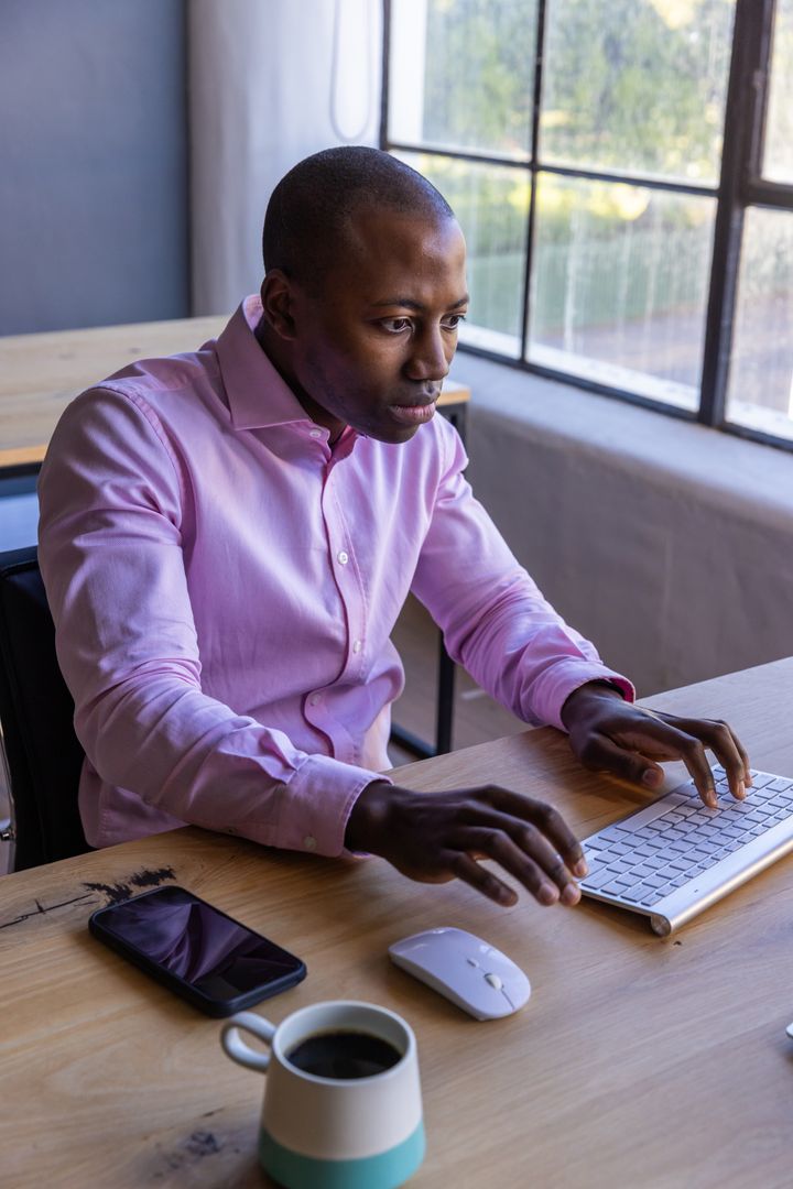 Focused Businessman at Workspace Typing on Wireless Keyboard