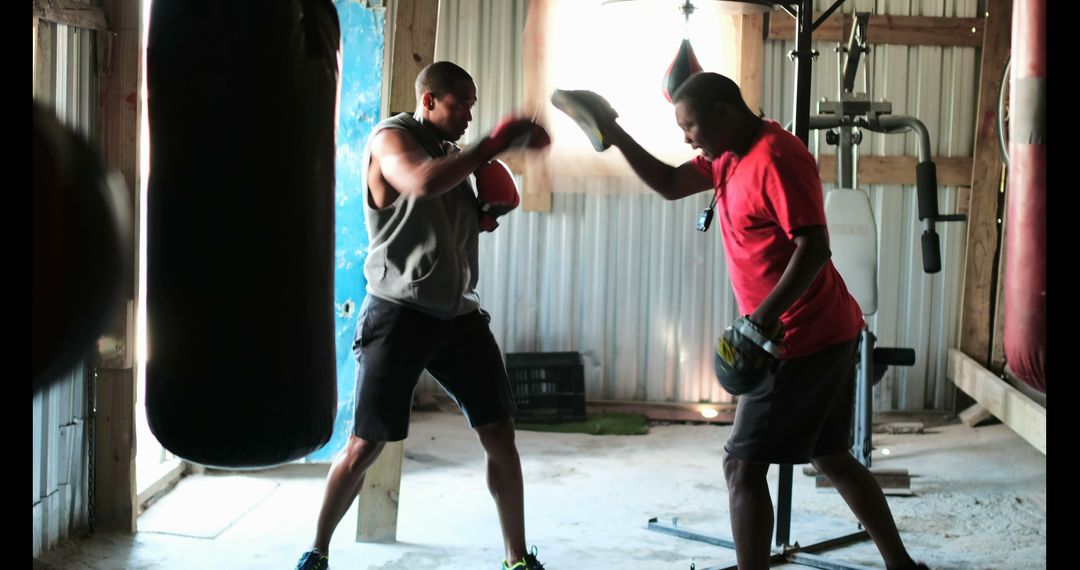 African American Boxer Training with Coach in Rustic Gym