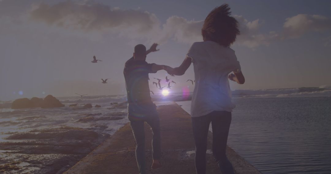 Couple Running Together on Coastal Rocks at Sunset
