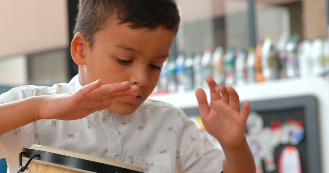 Young Schoolboy Intently Playing Bongo Drums in Classroom Setting