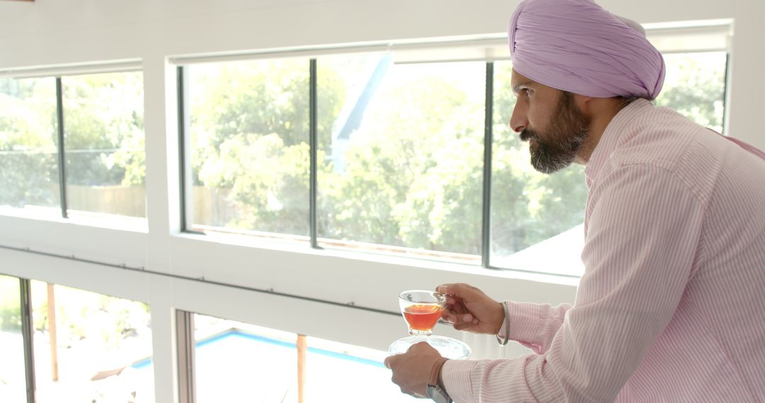 Indian Man in Turban Drinking Tea at Home Looking Out Window