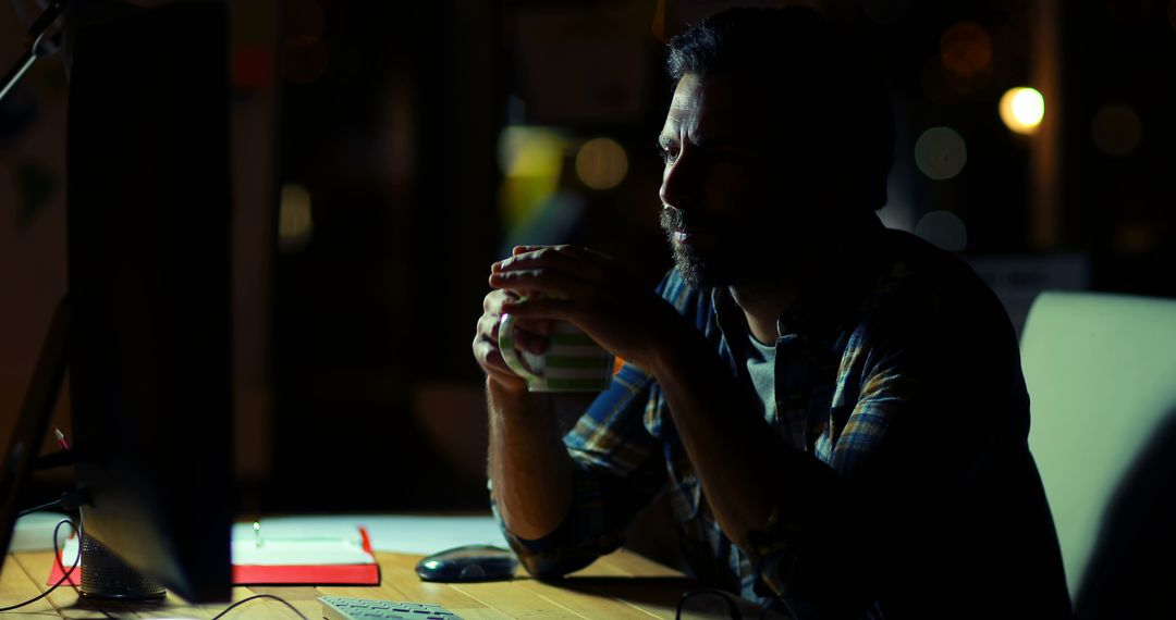 Man Drinking Coffee at Night While Working in Dark Office - Free Images, Stock Photos and Pictures on Pikwizard.com