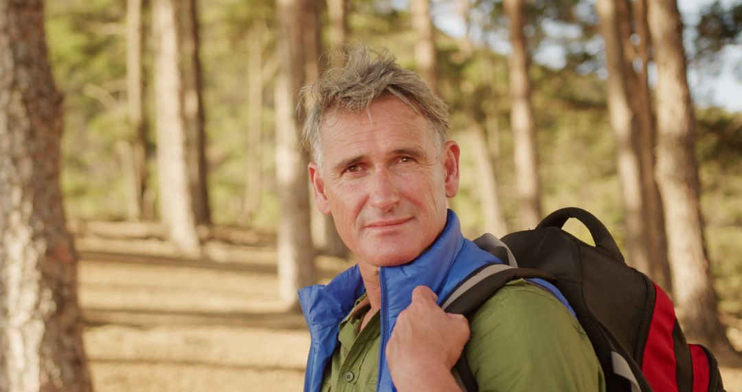 Senior Man Enjoying Solo Hike in Sunny Forest with Backpack