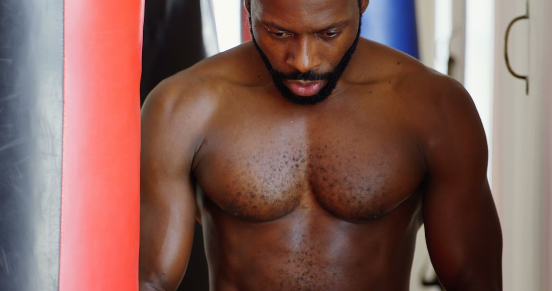 Determined Boxer Training with Punching Bag in Gym