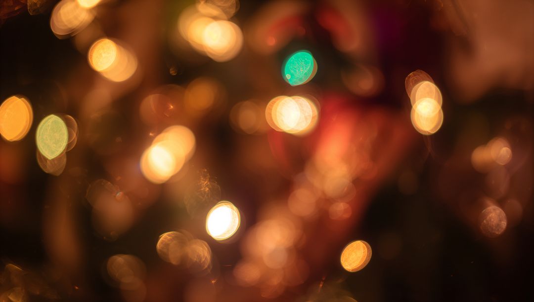 Warm holiday bokeh lights with gold and teal ornaments creating abstract festive glow