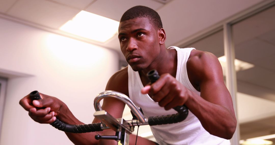 Focused Young Man Exercising on Stationary Bike in Gym - Free Images, Stock Photos and Pictures on Pikwizard.com