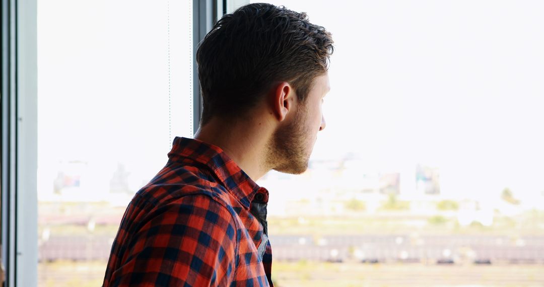 Thoughtful Man Looking Out Window in Bright Interior