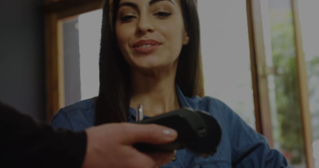 Smiling Woman Paying with Smartphone in Café